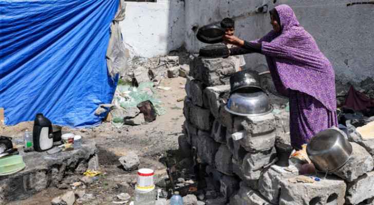Woman washes pots outside tent set up in Rafah, south of the Gaza Strip (Credit: AFP)
