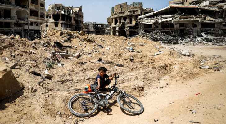 A boy sits with a bicycle on the ground by destroyed buildings in Khan Yunis, south Gaza. (April 22, 2024) (Photo: AFP)