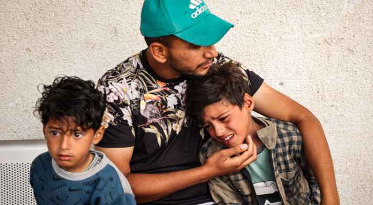 Palestinian hugging his children after their mother's martyrdom in Gaza