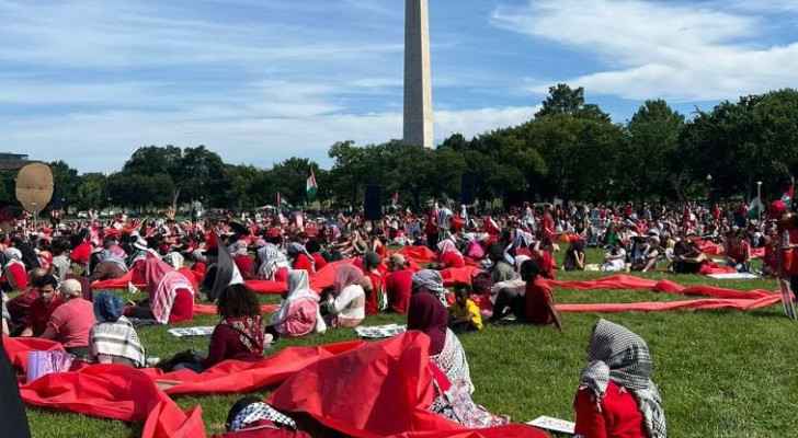 Protestors lay on the grass of the National Mall in front of the Washington Monument holding a symbolic red line