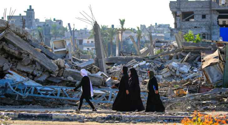 Palestinian women walking through the rubble.